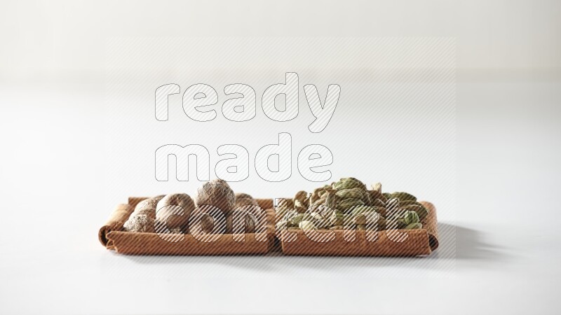 2 squares of cinnamon sticks full of cardamom and nutmegs on white flooring