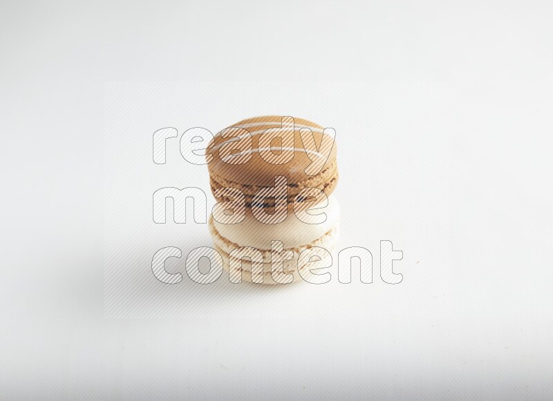 45º Shot of of two assorted Brown Irish Cream, and White Caramel fleur de sel macarons on white background