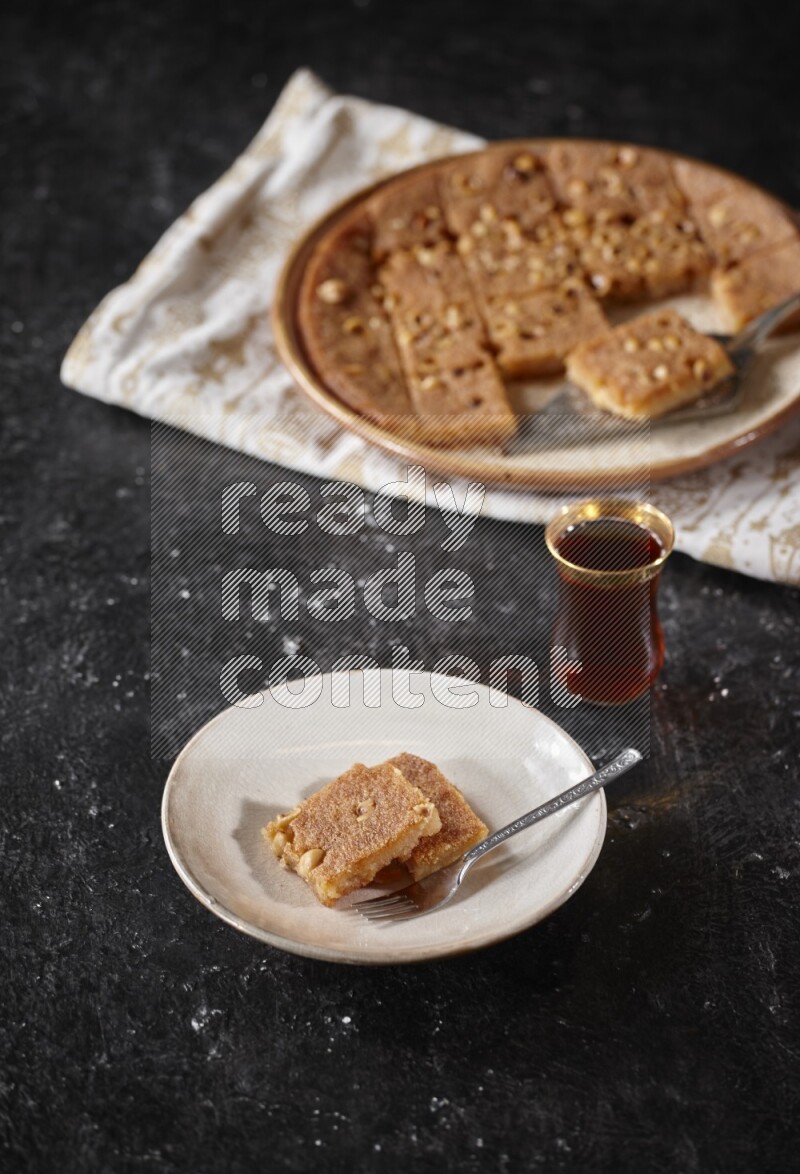 Basbousa with tea in a dark setup