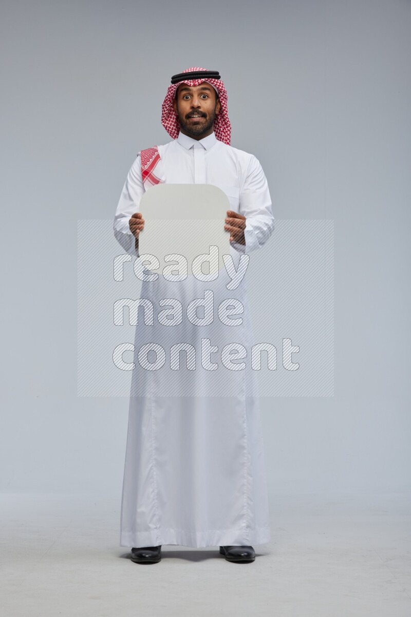 Saudi man Wearing Thob and shomag standing holding social media sign on Gray background