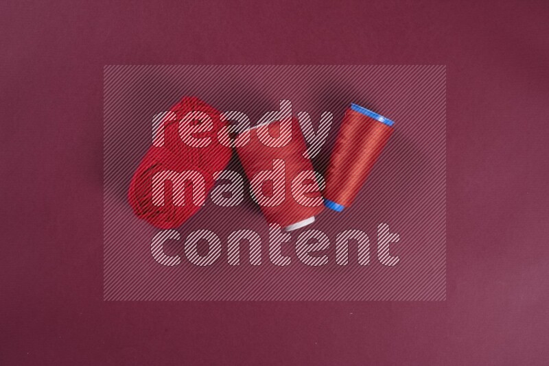 A red collection of sewing and tailoring tools arranged on a red background