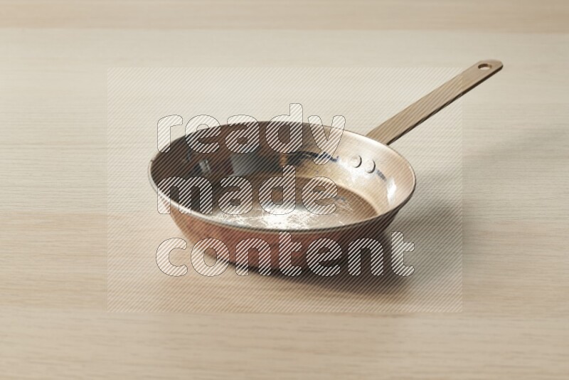 A small copper pan on light wooden background