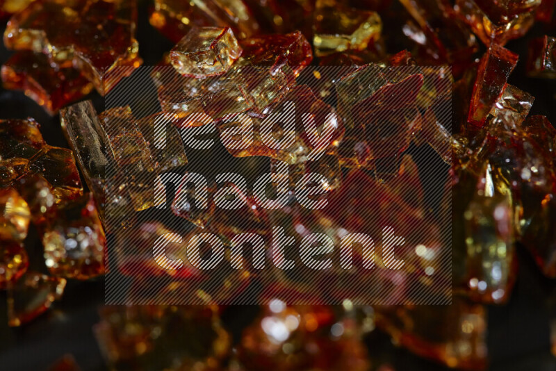 Transparent orange fragments of glass scattered on a black background