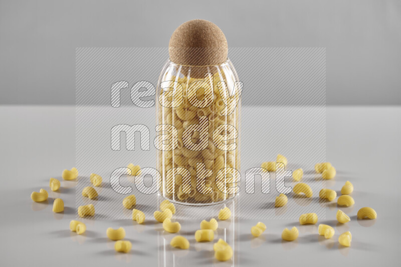 Raw pasta in a glass jar on light grey background