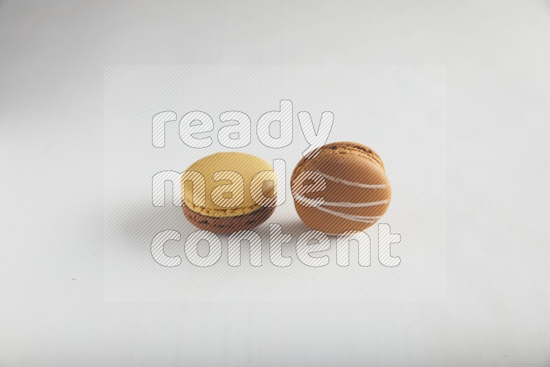 45º Shot of of two assorted Brown Irish Cream, and Yellow, and Brown Chai Latte macarons on white background