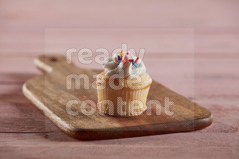Vanilla mini cupcake topped with cream on a wooden board