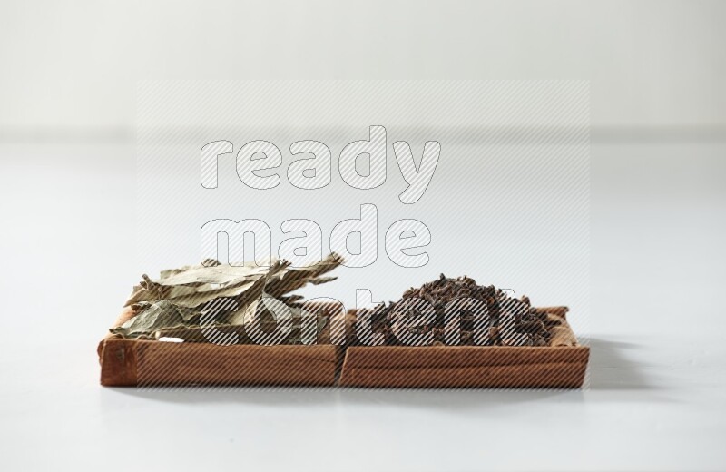 2 squares of cinnamon sticks full of cloves and bay laurel leaves on white flooring