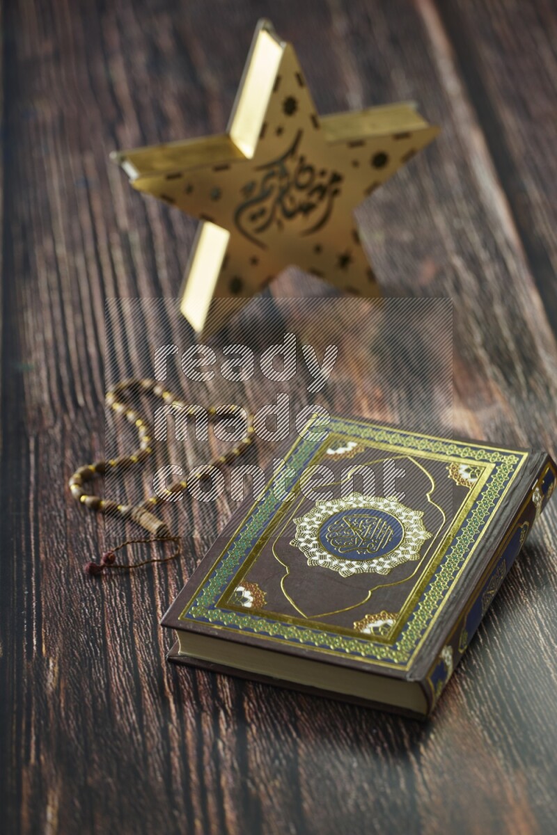 A wooden golden star lantern with different drinks, dates, nuts, prayer beads and quran on brown wooden background
