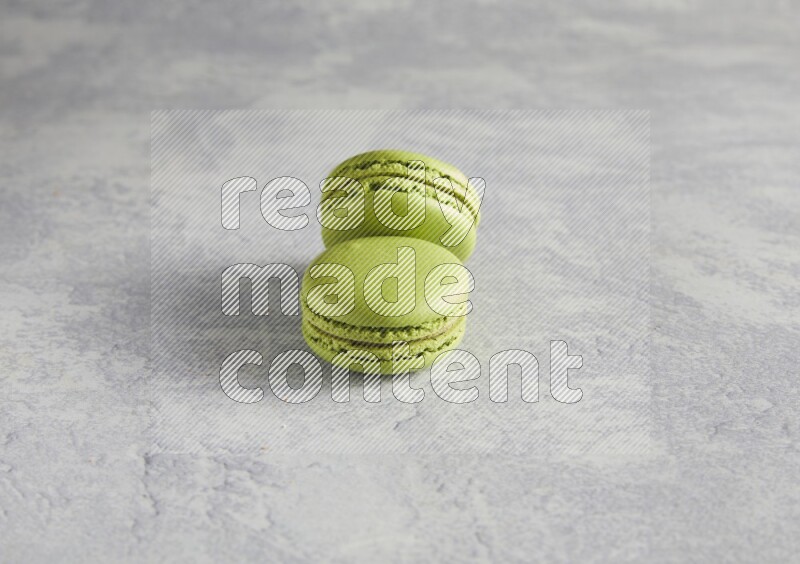 45º Shot of two Green Pistachio macarons  on white  marble background