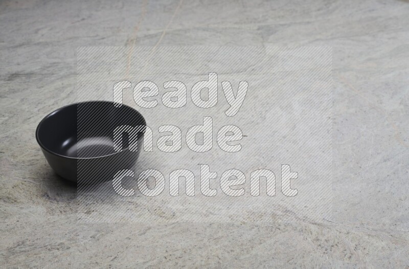A black ceramic bowl on grey marble background