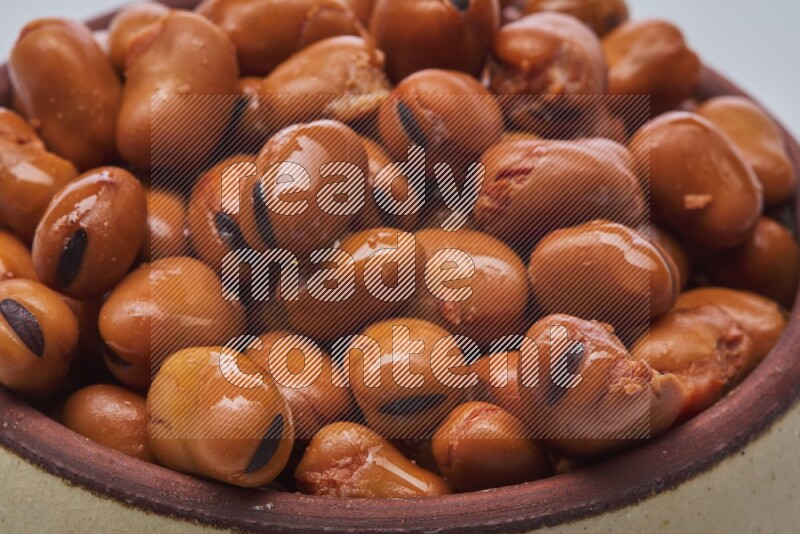 Close up shot of cooked fava beans (foul) in a container on white background