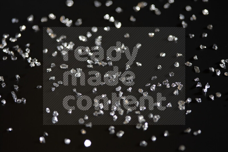 Silver shimmering fragments of glass scattered on a black background