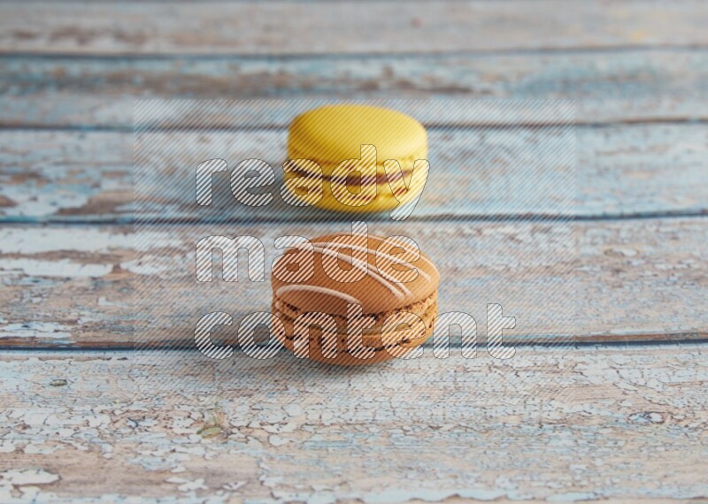 45º Shot of of two assorted Brown Irish Cream, and Yellow Lemon macarons on light blue background