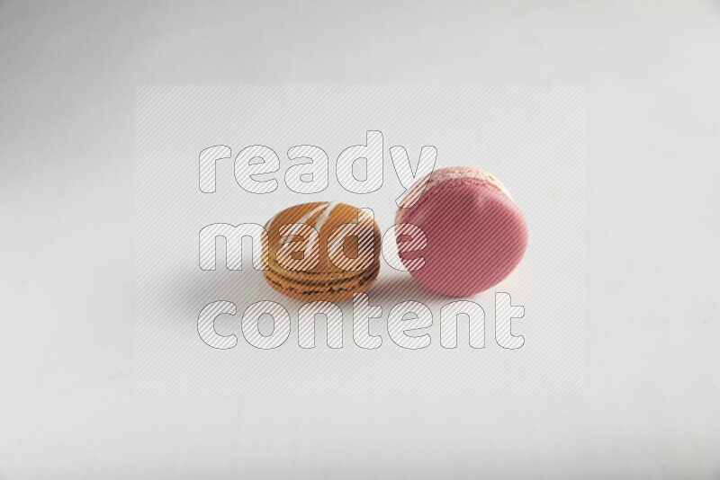 45º Shot of of two assorted Brown Irish Cream, and Pink Litchi Raspberry macarons on white background