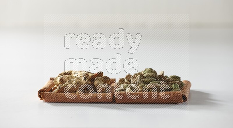 2 squares of cinnamon sticks full of cardamom and turmeric fingers on white flooring