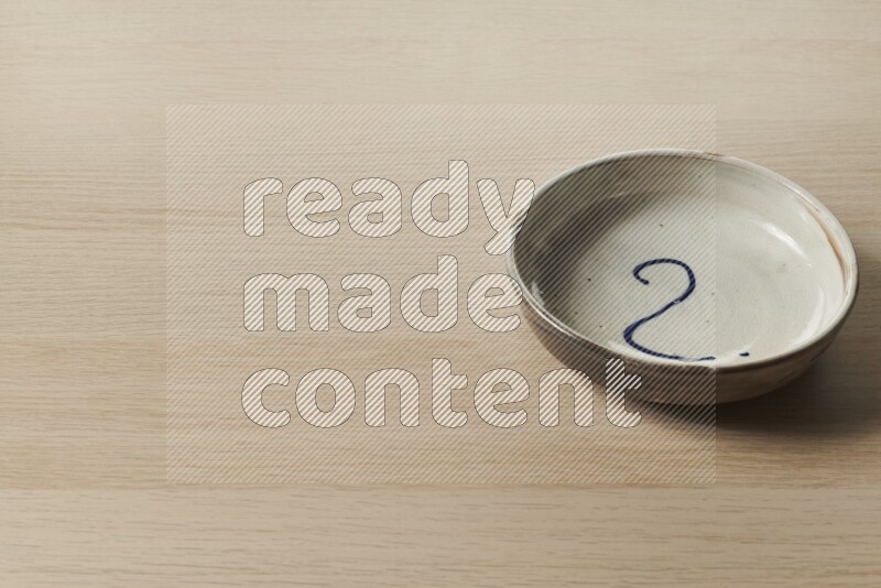 A multicolored pottery bowl on light wooden background