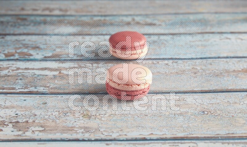 45º Shot of two Pink Litchi Raspberry macarons on light blue wooden background