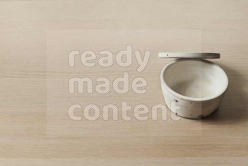 A white pottery bowl on light wooden background
