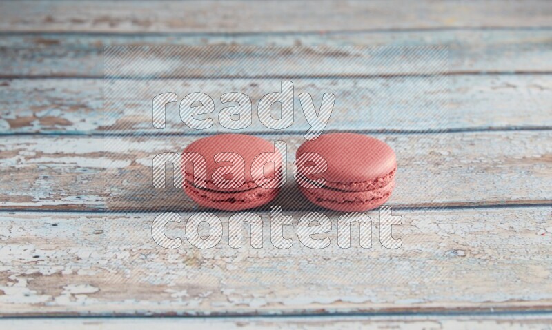 45º Shot of two Pink Raspberry macarons on light blue wooden background