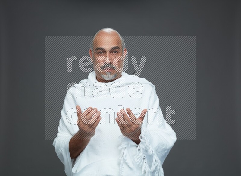 A man wearing Ehram Standing dua'a on gray background