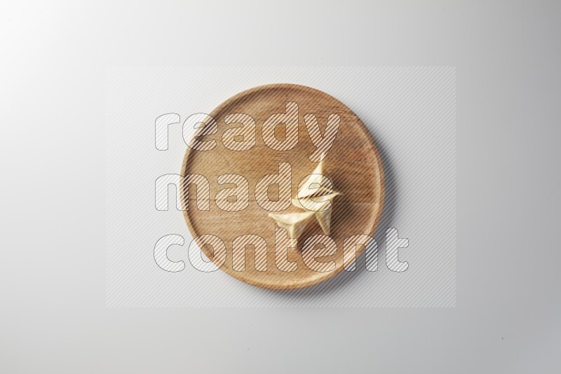 Three Sambosas on a wooden round plate on a white background