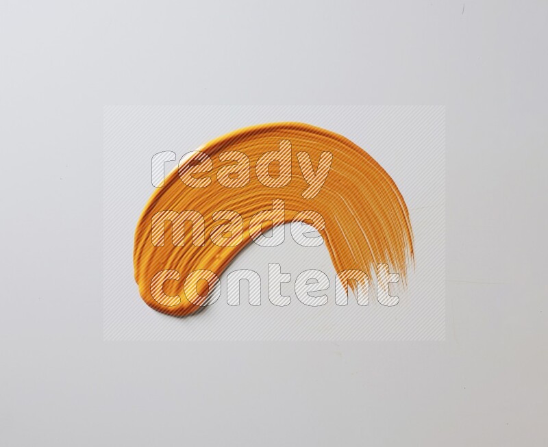 An orange curved painting brush stroke on a white background