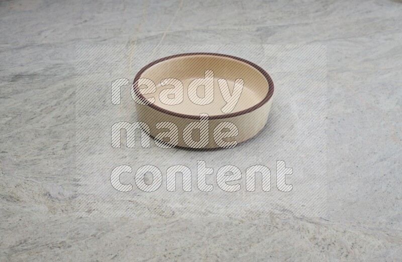 A beige pottery oven bowl on grey marble background