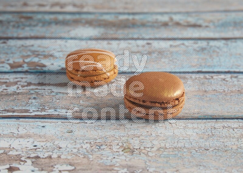 45º Shot of of two assorted Brown Irish Cream, and Brown Coffee macarons on light blue background