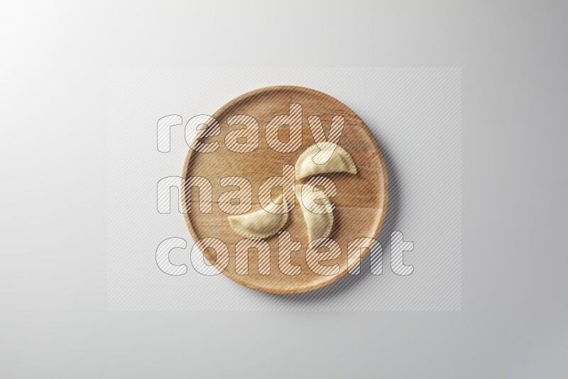 Three Sambosas on a wooden round plate on a white background