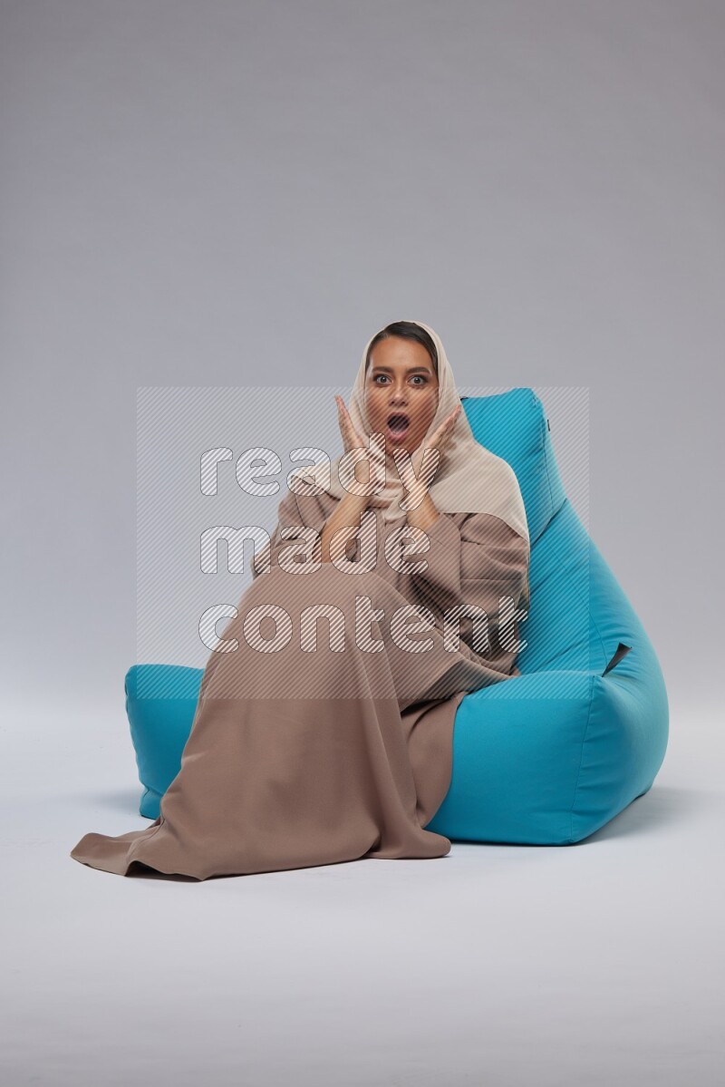 A woman sitting on a blue beanbag and interacting with the camera