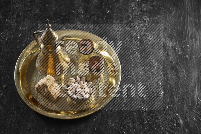 Oriental sweets with nuts and a drink on a metal tray in a dark setup