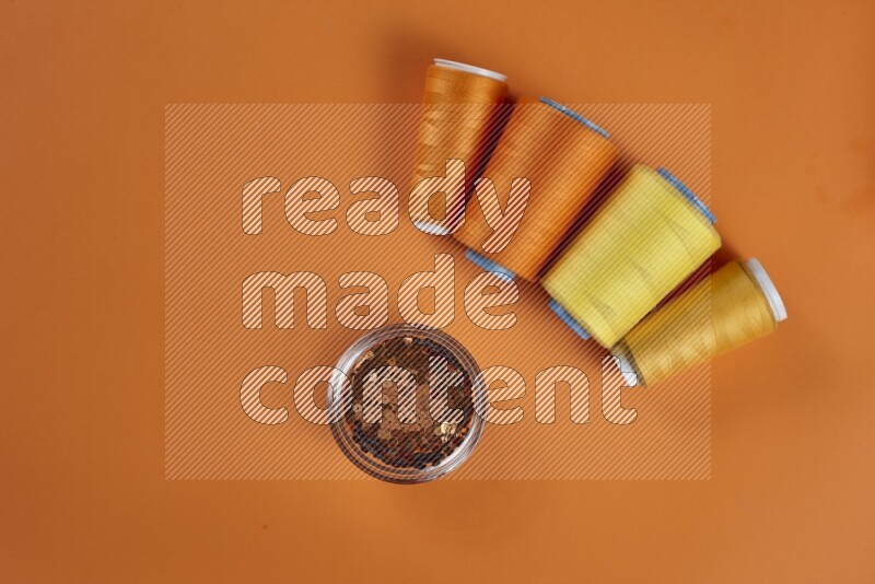 مجموعة من أدوات الخياطة والتفصيل صفراء اللون على خلفية برتقالية