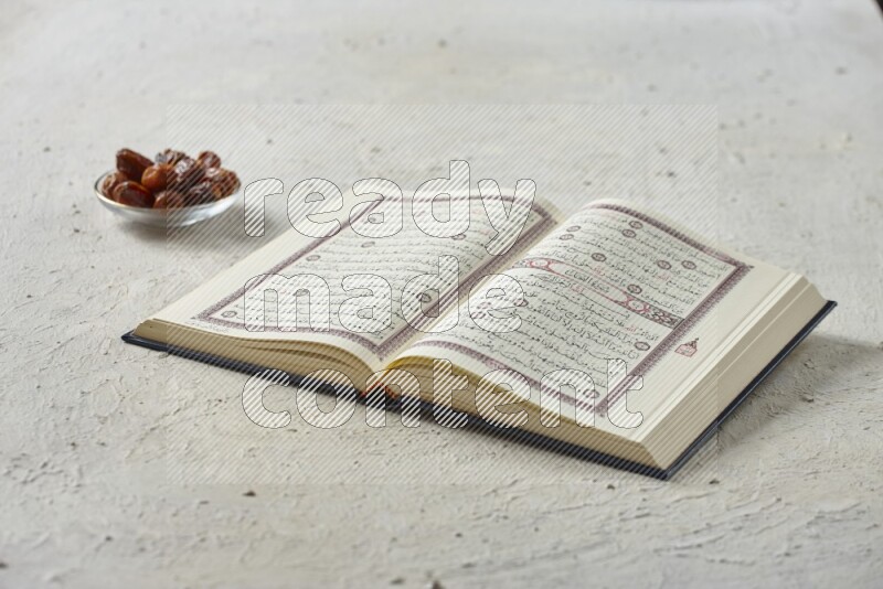 Quran with dates, prayer beads and different drinks all placed on textured white background
