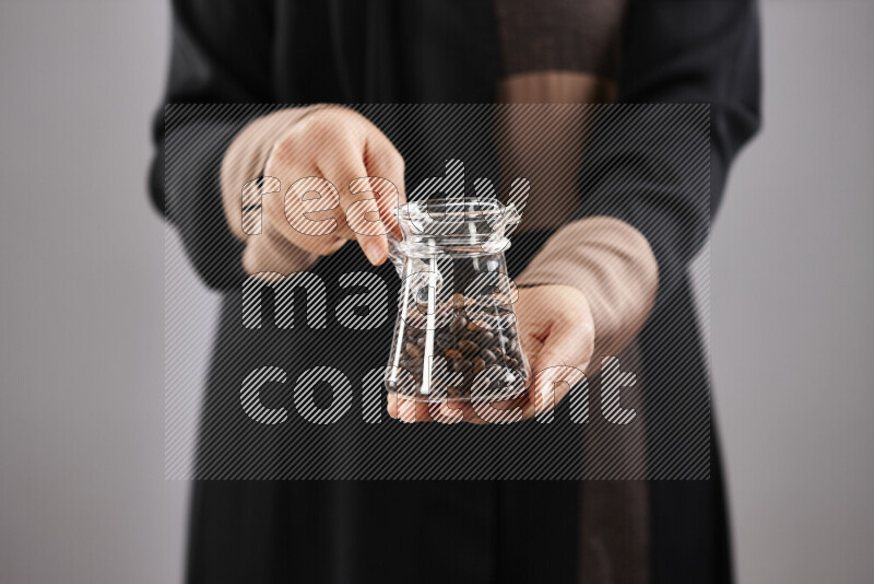 Woman in abaya holding different kinds of coffee beans in different positions