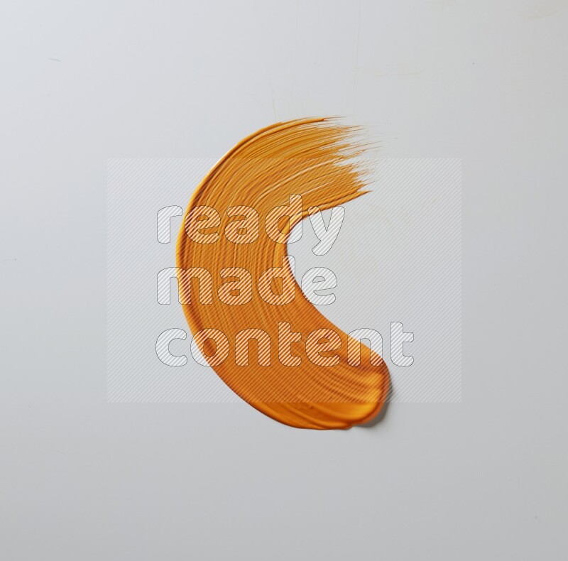 An orange curved painting brush stroke on a white background