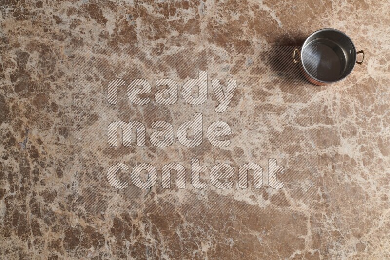 A small copper pot on beige marble background