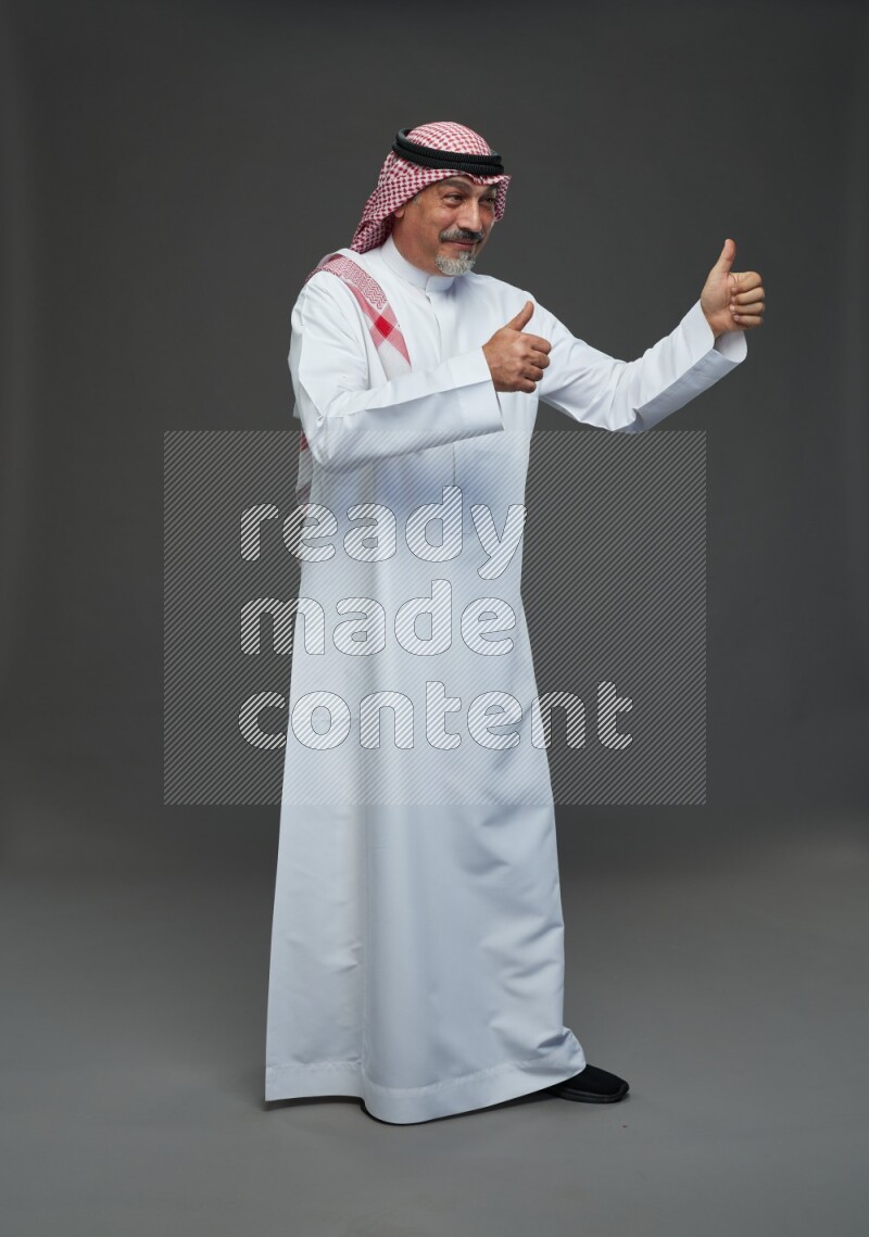 Saudi man with shomag Standing Interacting with the camera on gray background