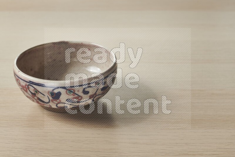 A decorative pottery bowl on light wooden background