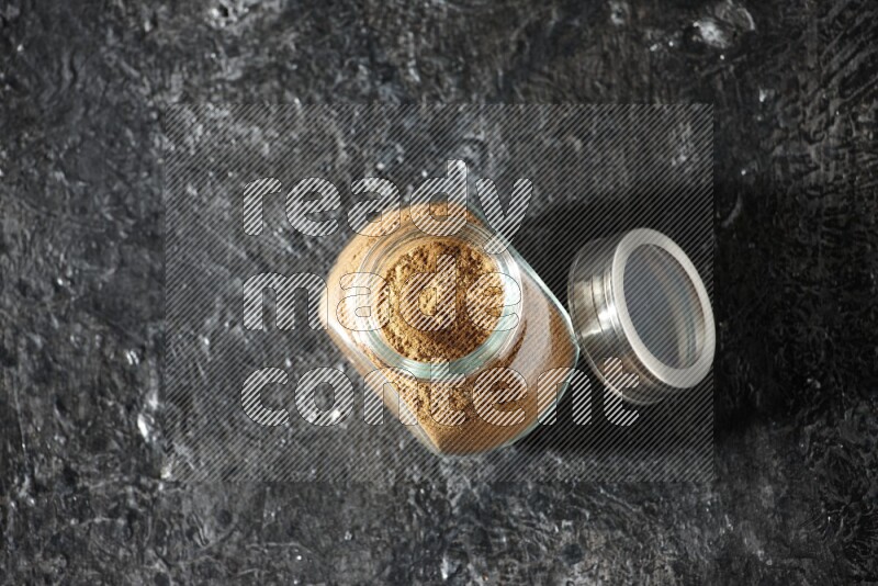 وعاء زجاجي للتوابل ممتلئ ببودرة بهار الفلفل الحلو على خلفية سوداء