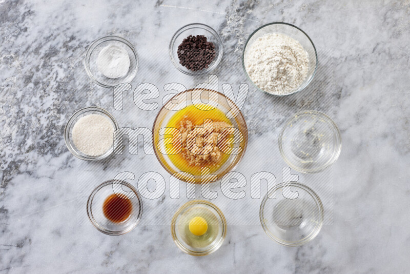 Cookies step by step with its ingredient, flour, butter, brown sugar, egg, vanilla extract, white sugar, chocolate chips and baking soda on grey marble background