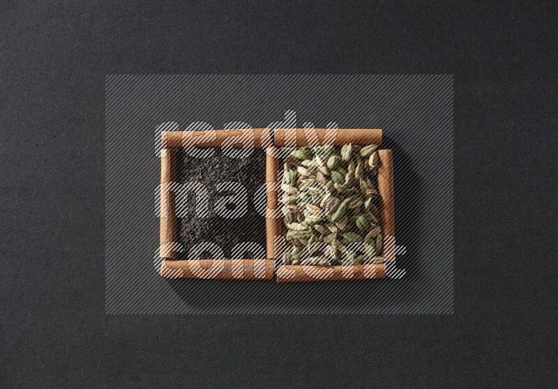 2 squares of cinnamon sticks full of cardamom and black tea on black flooring