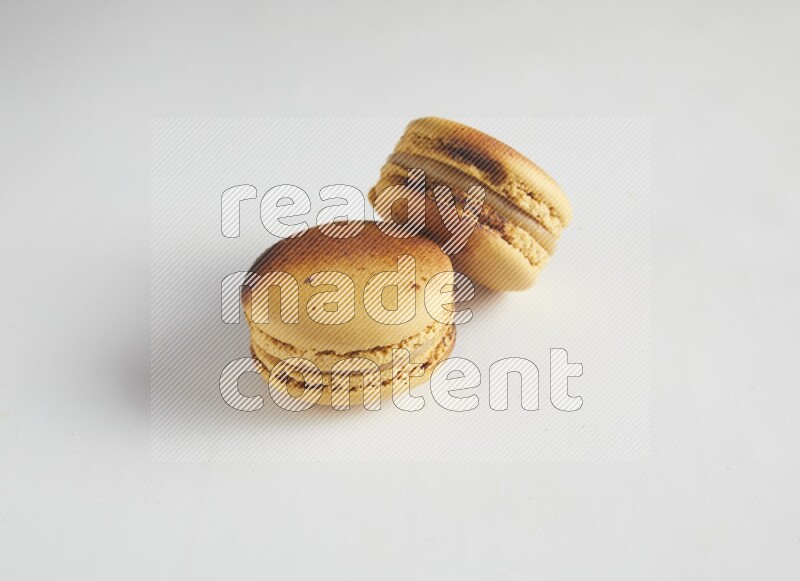 45º Shot of two Yellow Crème Brulée macarons on white background