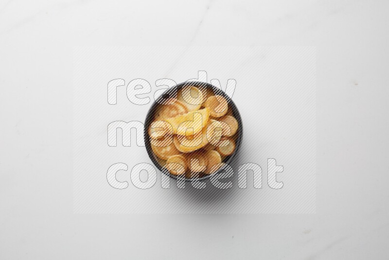 Top-view shot of orange candy cereal pancakes in a round bowl on white background