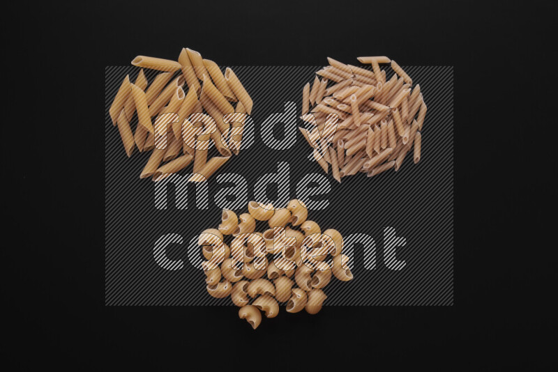 Different pasta types in bunches on black background