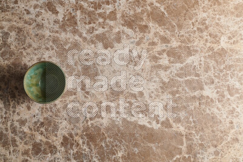 A dark green pottery bowl on beige marble background