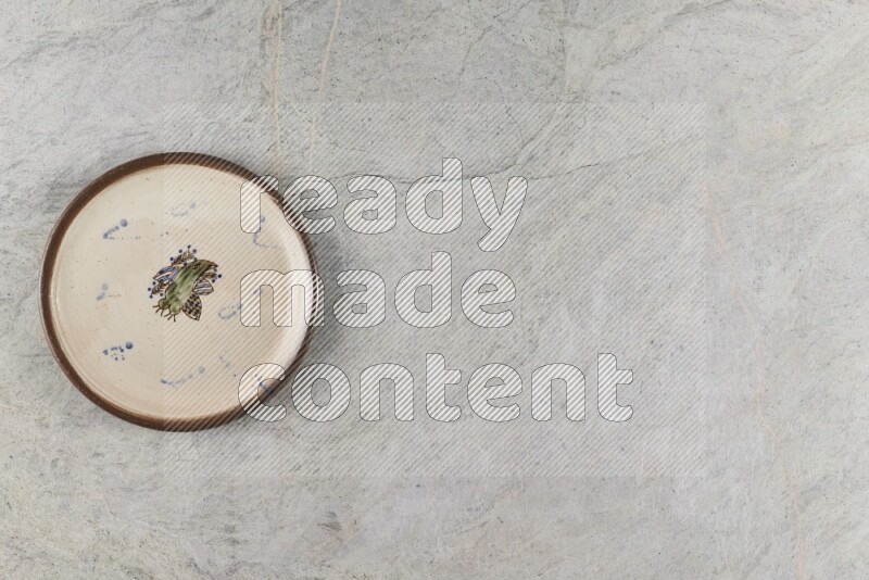 A decorative pottery plate on grey marble background