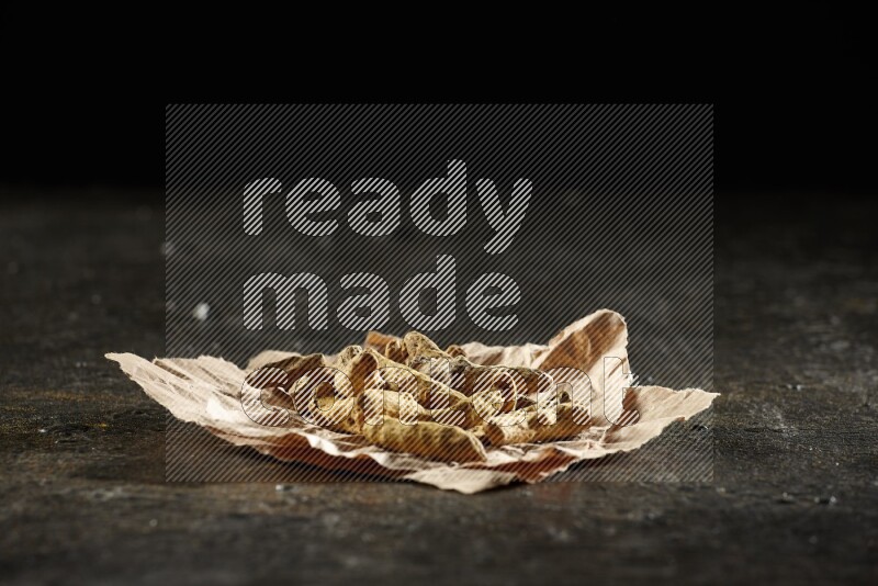 أصابع الكركم المجففة في قطعة من الورق على خلفية سوداء