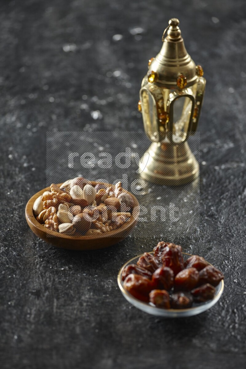 A golden lantern with different drinks, dates, nuts, prayer beads and quran on textured black background