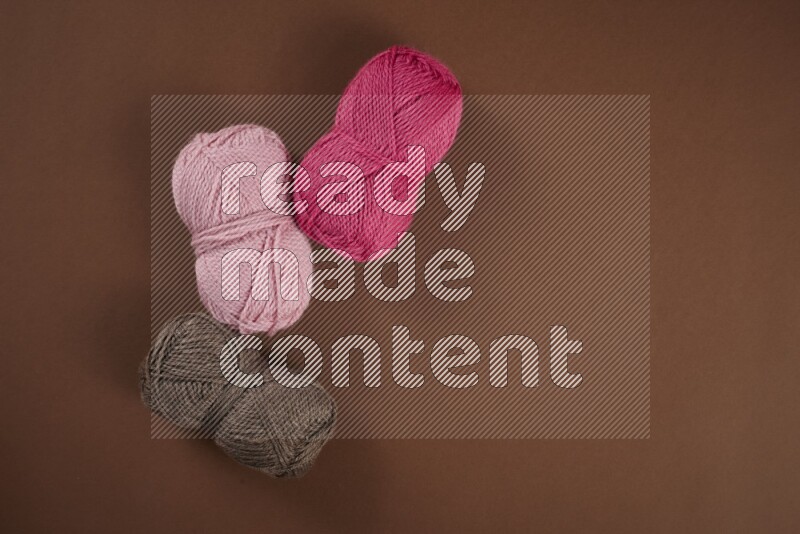 A pink collection of sewing and tailoring tools arranged on a brown background