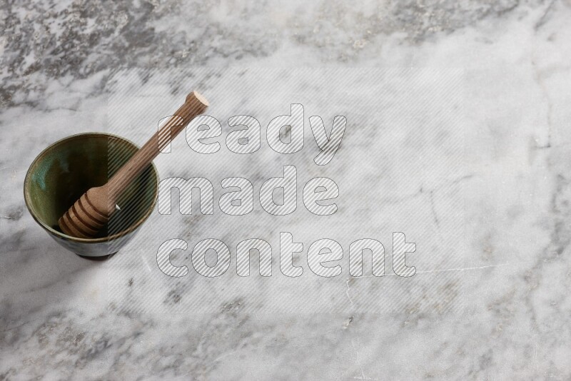 Decorative pottery bowl with wooden honey dipper in it on grey marble background